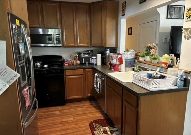 kitchen featuring kitchen peninsula, light wood-type flooring, sink, and appliances with stainless steel finishes