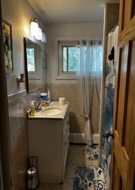 bathroom with walk in shower, vanity, a wealth of natural light, and tile walls