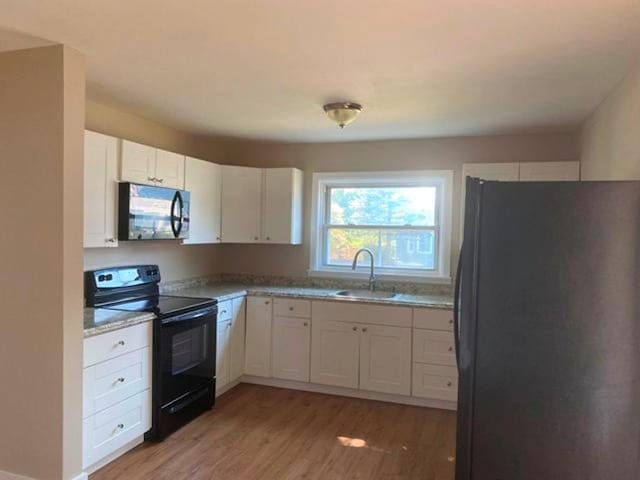 kitchen with white cabinets, wood-type flooring, sink, and black appliances