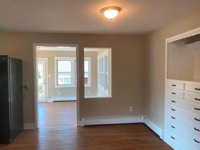 unfurnished room with dark wood-type flooring and a baseboard radiator