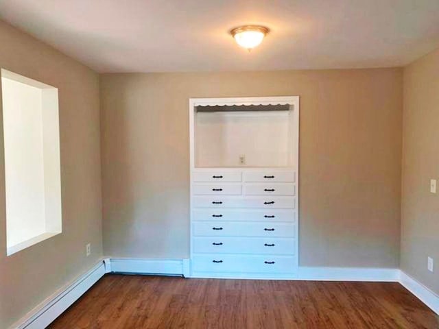 unfurnished bedroom with dark hardwood / wood-style flooring, a baseboard radiator, and a closet