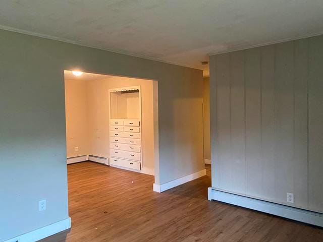 empty room with hardwood / wood-style flooring and a baseboard heating unit