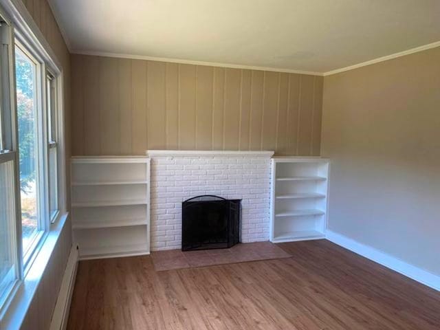 unfurnished living room with a fireplace, hardwood / wood-style floors, baseboard heating, and crown molding