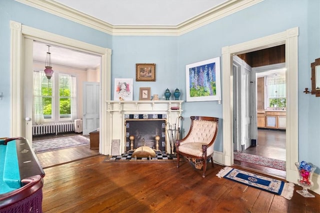 living area with crown molding, radiator heating unit, and wood-type flooring