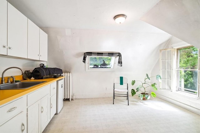 kitchen with white cabinetry, sink, radiator heating unit, and a healthy amount of sunlight