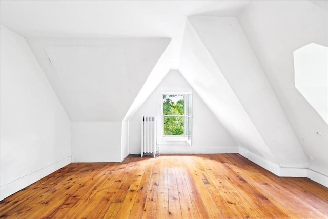 bonus room with lofted ceiling, radiator, and light wood-type flooring