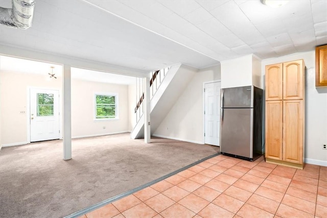 kitchen with stainless steel refrigerator, light brown cabinetry, and light carpet