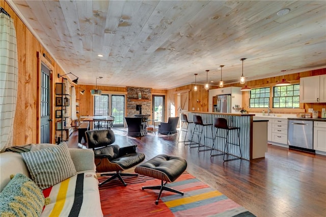 living room with a wood stove, sink, dark hardwood / wood-style flooring, wood walls, and wood ceiling