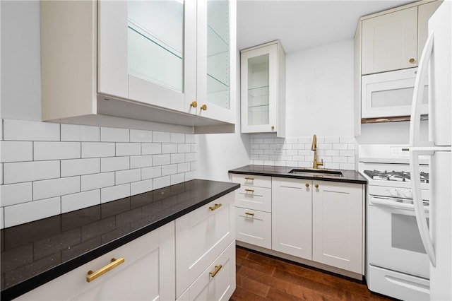 kitchen with sink, dark hardwood / wood-style flooring, backsplash, white appliances, and white cabinets