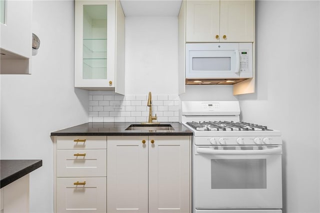 kitchen with white appliances, backsplash, dark stone counters, white cabinets, and sink