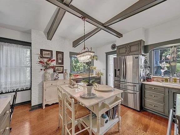 kitchen with a chandelier, stainless steel fridge with ice dispenser, dark hardwood / wood-style flooring, and brick wall