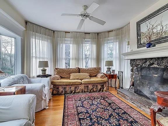 sunroom with a stone fireplace and ceiling fan