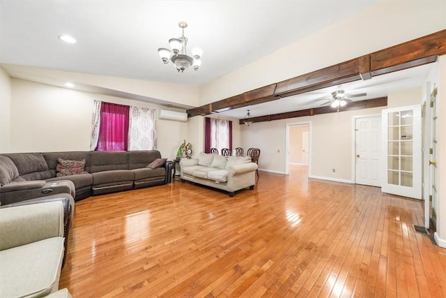 living room with hardwood / wood-style floors, ceiling fan with notable chandelier, beamed ceiling, and a wall mounted AC