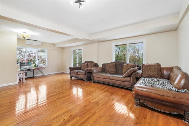 living room featuring light hardwood / wood-style floors, a wall unit AC, and a wealth of natural light