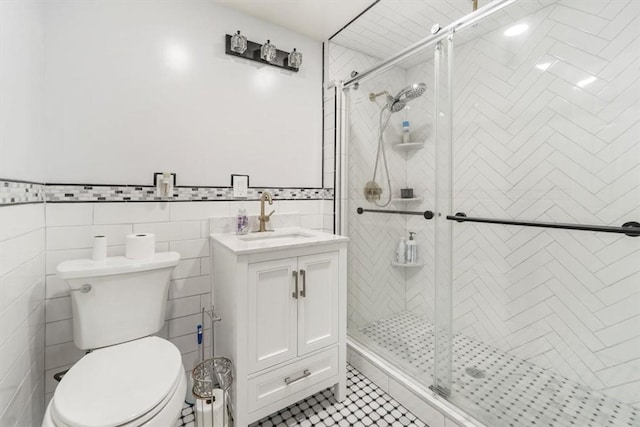 bathroom featuring walk in shower, tile patterned floors, toilet, vanity, and tile walls