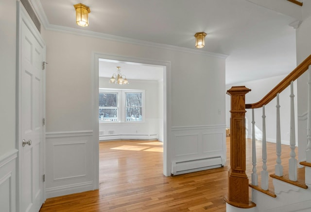 interior space featuring a baseboard radiator, ornamental molding, and light hardwood / wood-style flooring