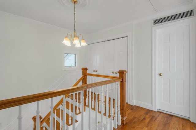 hall with crown molding, wood-type flooring, and a chandelier