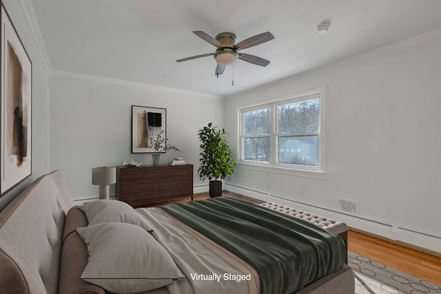 bedroom with hardwood / wood-style floors, ornamental molding, and ceiling fan