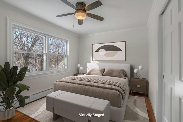 bedroom with a baseboard heating unit, ornamental molding, ceiling fan, and light wood-type flooring