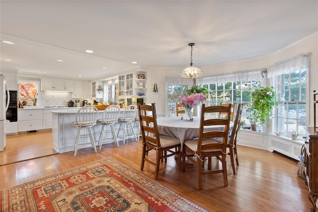 dining room with ornamental molding, a notable chandelier, radiator heating unit, and light hardwood / wood-style floors