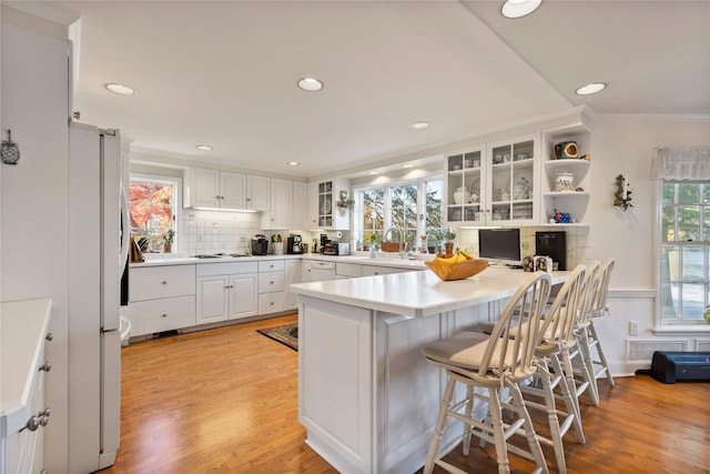 kitchen featuring white cabinetry, light hardwood / wood-style floors, refrigerator, and kitchen peninsula