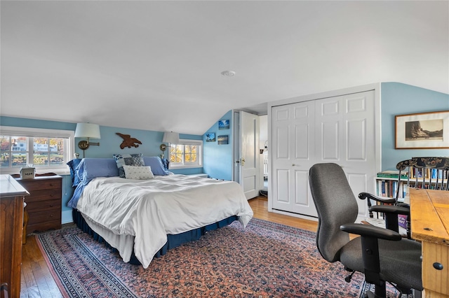 bedroom with multiple windows, lofted ceiling, hardwood / wood-style floors, and a closet