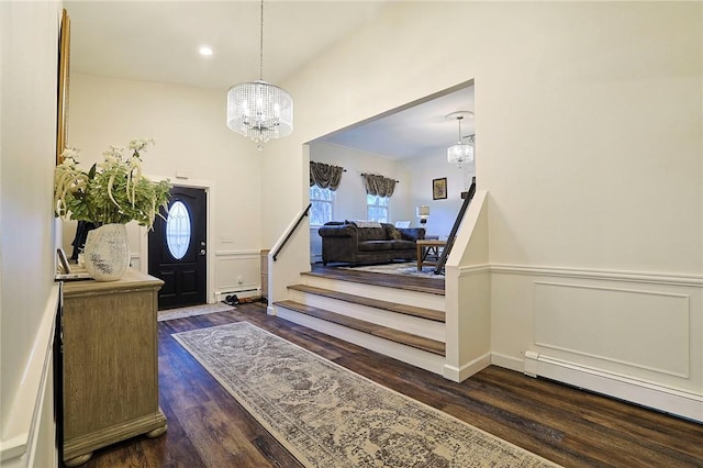 foyer with an inviting chandelier, baseboard heating, and dark wood-type flooring