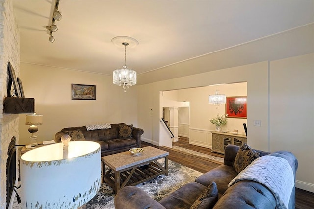 living room with dark hardwood / wood-style floors, track lighting, and a chandelier