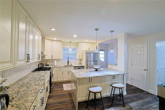 kitchen featuring a kitchen bar, dark hardwood / wood-style flooring, stainless steel appliances, sink, and white cabinetry