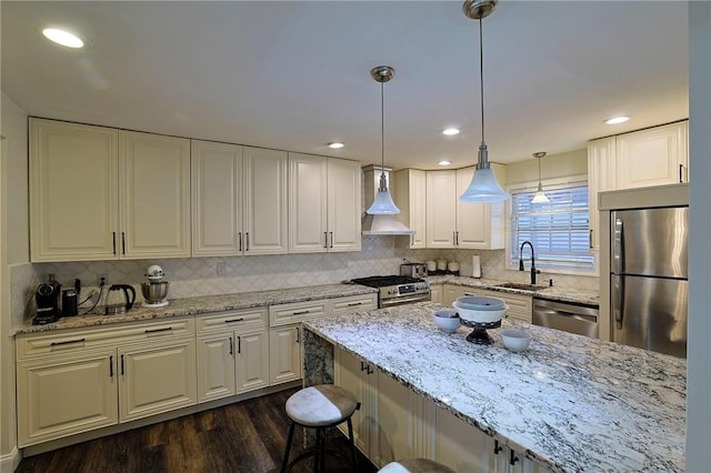 kitchen featuring wall chimney range hood, sink, hanging light fixtures, dark hardwood / wood-style floors, and appliances with stainless steel finishes