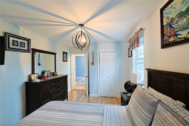 bedroom featuring a closet, light hardwood / wood-style floors, and an inviting chandelier