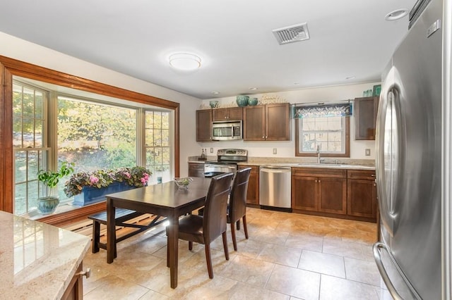 kitchen with light stone countertops, plenty of natural light, sink, and appliances with stainless steel finishes