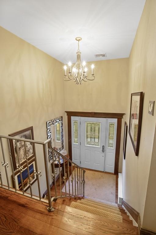 carpeted entryway with a chandelier