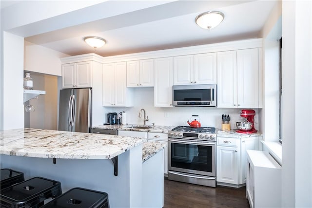 kitchen with white cabinetry, sink, dark wood-type flooring, stainless steel appliances, and a breakfast bar area