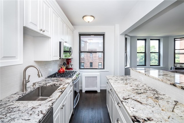 kitchen featuring sink, appliances with stainless steel finishes, tasteful backsplash, dark hardwood / wood-style flooring, and white cabinetry