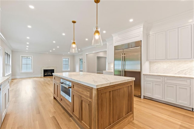 kitchen featuring decorative backsplash, appliances with stainless steel finishes, decorative light fixtures, white cabinetry, and a large island