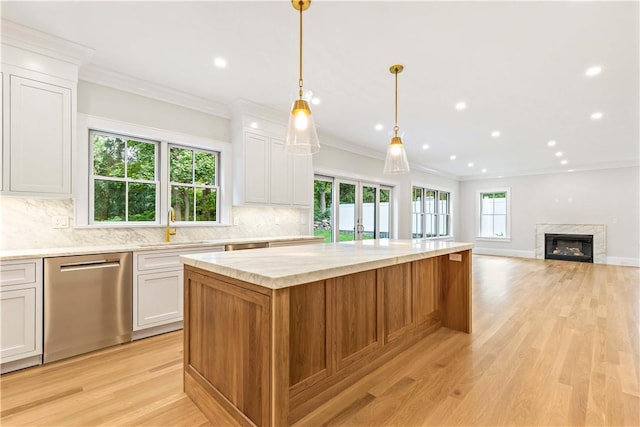 kitchen featuring stainless steel dishwasher, decorative light fixtures, white cabinetry, and a premium fireplace