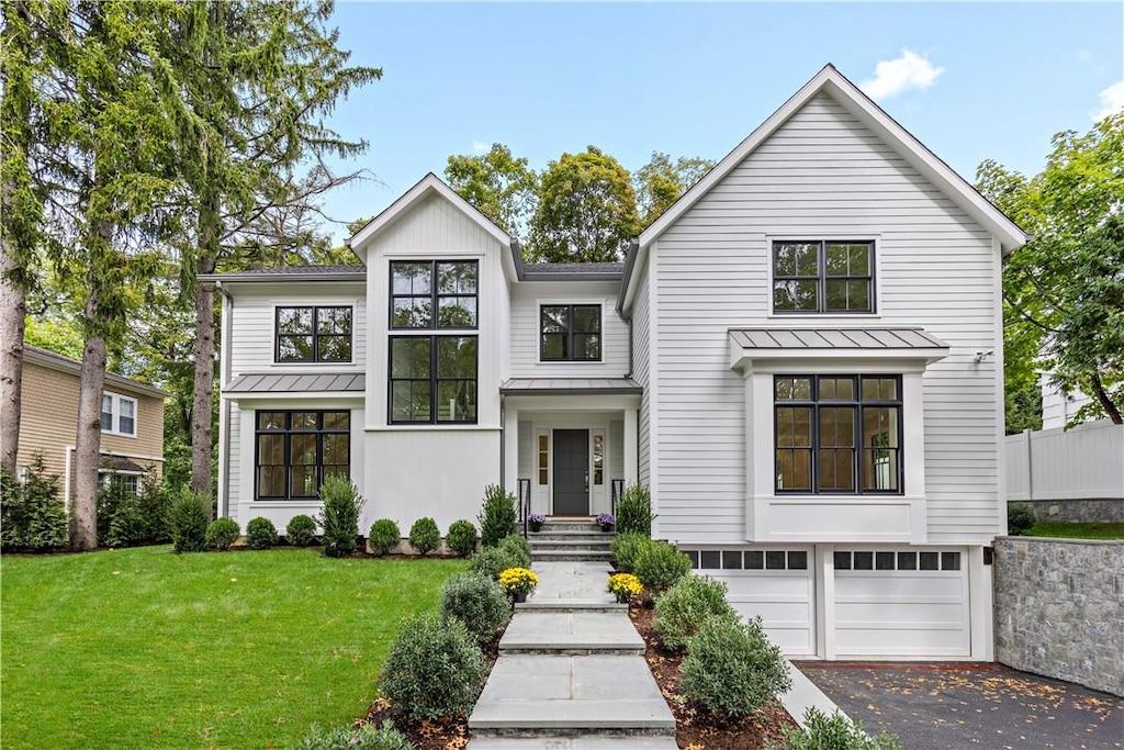 modern farmhouse featuring a garage and a front lawn