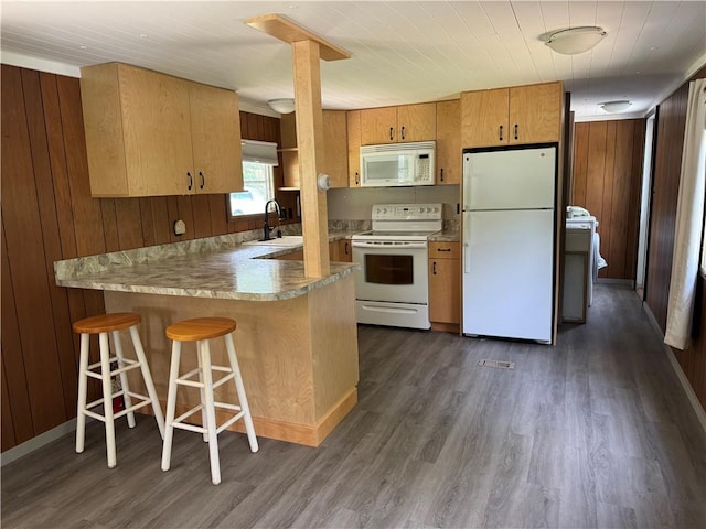 kitchen featuring kitchen peninsula, wooden walls, dark hardwood / wood-style flooring, and white appliances