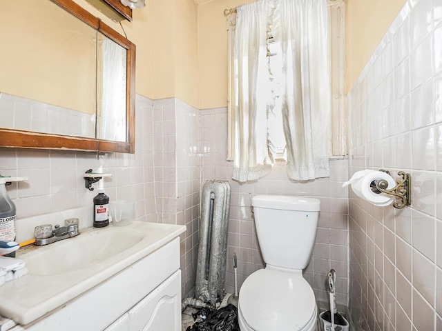 bathroom featuring vanity, toilet, and tile walls