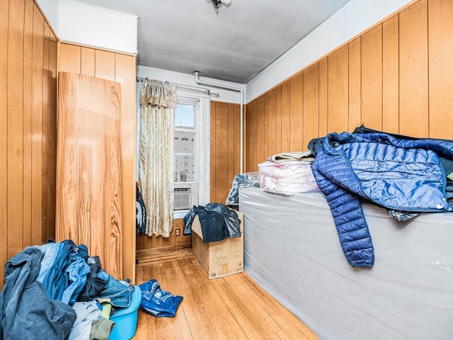 bedroom with light hardwood / wood-style flooring, cooling unit, and wood walls