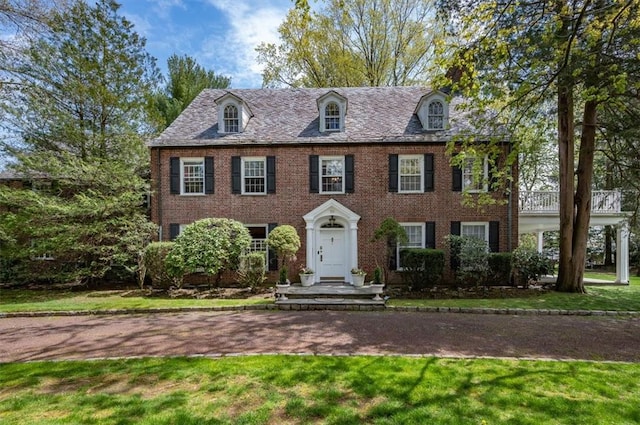 colonial-style house featuring a front yard