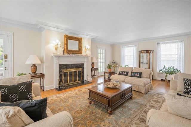 living room with light hardwood / wood-style floors, crown molding, and a high end fireplace