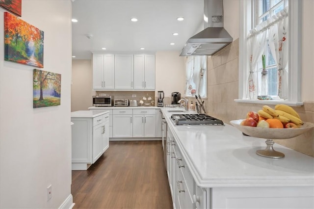 kitchen with backsplash, stainless steel appliances, dark wood-type flooring, wall chimney range hood, and white cabinets