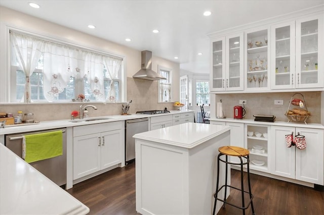 kitchen with white cabinets, a center island, wall chimney range hood, and stainless steel appliances