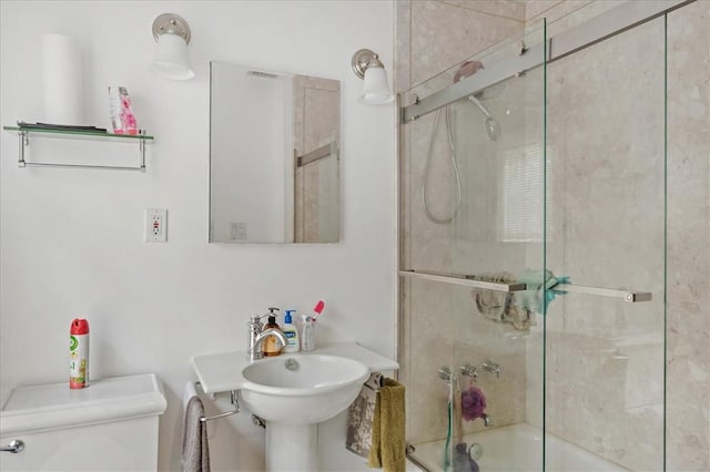 bathroom featuring toilet and bath / shower combo with glass door