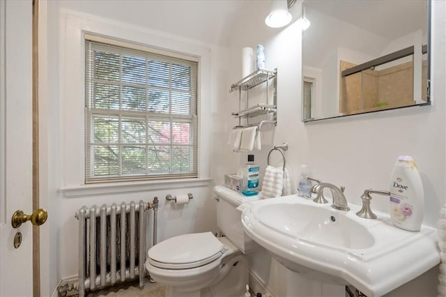 bathroom with toilet, radiator heating unit, a shower with door, and sink