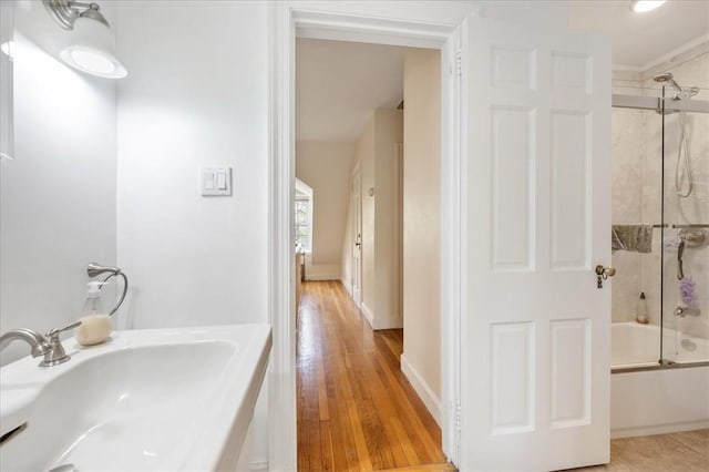 bathroom with combined bath / shower with glass door, hardwood / wood-style flooring, and sink