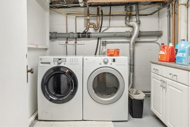 clothes washing area with washer and clothes dryer and cabinets