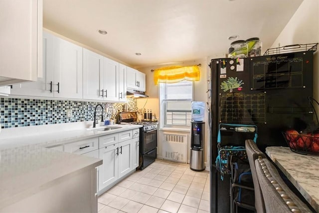 kitchen featuring white cabinets, sink, light tile patterned floors, radiator heating unit, and black range with gas cooktop